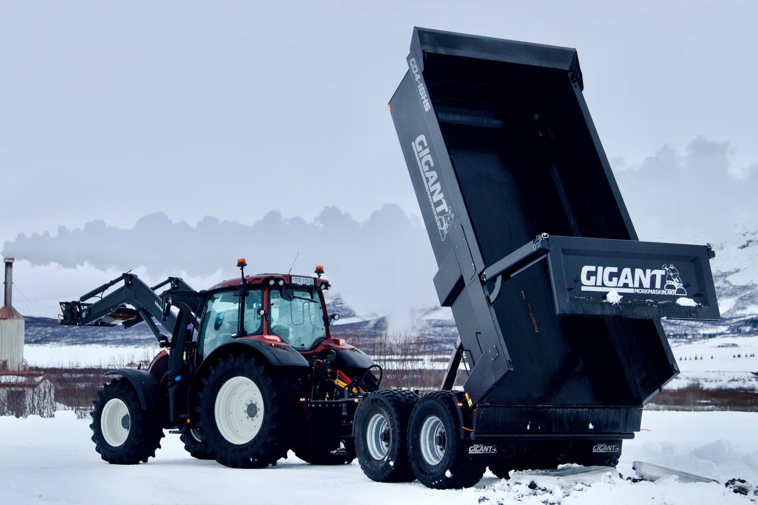 Traktor að losa svartan Gigant sturtuvagn í snjó